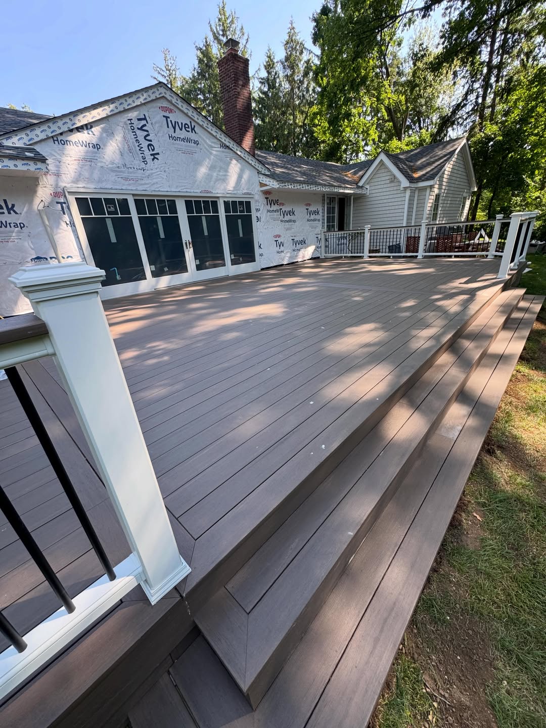 Completed wide composite deck with cascading stairs and white railing posts